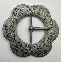 a metal object with flowers and leaves on it's side, in the shape of a circle