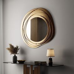 a round mirror on the wall above a table with a vase and lamp next to it