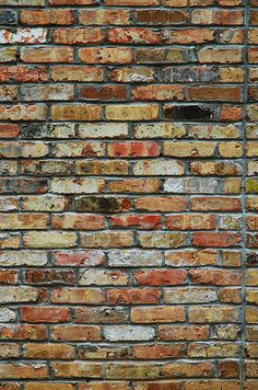 an old brick wall is painted red and yellow