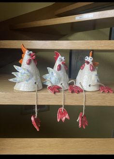 three ceramic roosters sitting on top of a shelf