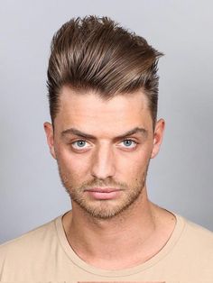 a close up of a person with a short haircut and blue eyes wearing a t - shirt