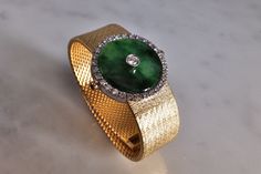 "Fine watch bracelet set with a jade donut and accented with diamonds in 18k. The donut is a deep green Omphacite jade, in parts dark and light like a globe lit. This jewel borrows the perfect finish of a Vacheron watch, its Omega straps in original burnished solid gold. More than a conversion piece, this bracelet could not have been refined to a sleeker layout. At 2cm, the donut is considered big yet its size is offset by the straps, and vice versa. The straps though wide feel made for its cent Elegant Green Diamond Watch For Formal Occasions, Fine Jade Jewelry For Formal Occasions, Formal Round Jade Jewelry, Luxury Green Diamond Watch For Formal Occasions, Green Luxury Diamond Watch For Formal Occasions, Timeless Green Jewelry For Evening, Timeless Green Evening Jewelry, Luxury Jade Jewelry, Luxury Jade Bracelets For Formal Occasions