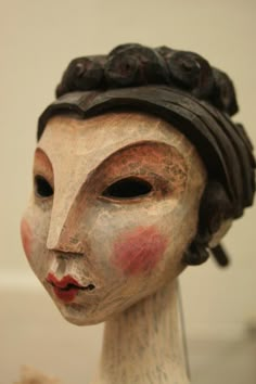 a close up of a ceramic head on a white surface with brown and red paint