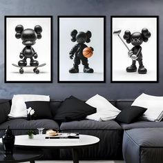 three black and white mickey mouse pictures hanging on the wall in a living room with couches