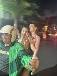 three people riding on the back of a motorcycle at night with their arms around each other