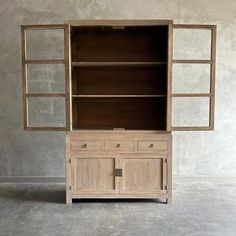 a wooden cabinet with two doors and drawers on the top, in front of a concrete wall