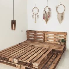 a bed made out of wooden pallets in a room with two hanging dream catchers on the wall