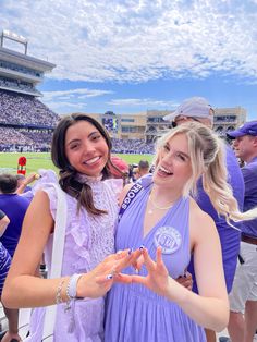 two women standing next to each other at a football game