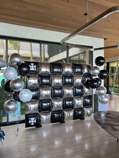 a room filled with lots of black and silver balloons