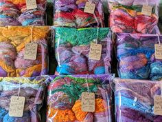 many different colored yarns in bags on display for sale at a market or store