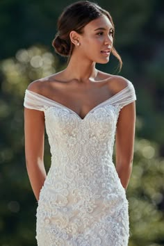 a woman in a white wedding dress is looking back at the camera with her hand on her hip