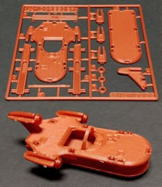 an orange plastic toy car next to it's cutout and instructions for the star wars land speeder kit