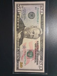 a one dollar bill is in a clear plastic case on a black surface with the image of a man's face