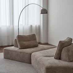 a living room scene with focus on the couch and floor lamp in the corner near the window