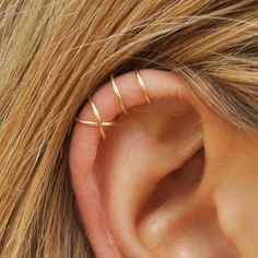 a woman's ear is shown with two thin gold hoops