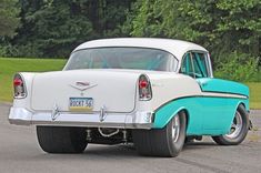 an old white and blue car driving down the road