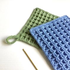 two crocheted squares sitting on top of each other next to a knitting needle