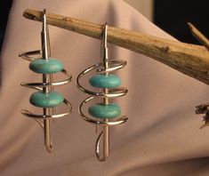 Shining silver swirls frame turquoise beads on these long dangle earrings, with an extra long earwire for balance. Jewel Crafts, Jewelry Magic, Wire Earrings Handmade, Simple Jewellery, Wire Wrap Jewelry Designs, Wrapping Jewelry, Whimsical Jewelry, Copper Art, Swirl Earrings