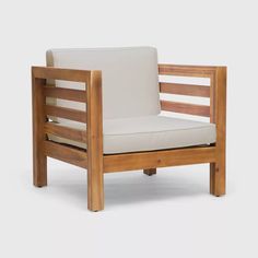 a wooden chair with a white cushion on the back and armrests, in front of a gray background