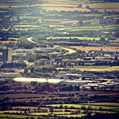 an aerial view of a city with lots of trees and fields in the foreground