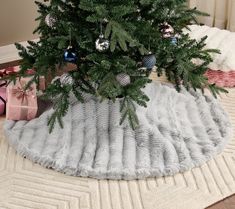 a small christmas tree on a rug in the middle of a room with presents under it