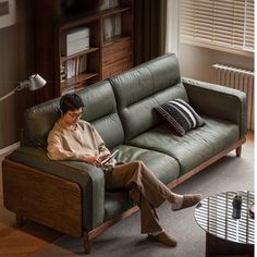 a man sitting on a green couch in front of a window