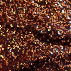 an orange and black sequinized fabric with lots of small round beads on it