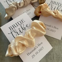 wedding favors with satin ribbons on them sitting on a table next to some cards that say bride tribe