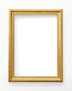 an empty gold frame hanging on the wall in front of a white wall and floor