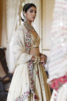 Ivory attached cancan lehenga with butterfly and leaf motif in resham embroidery highlighted with mirror and sequin work. Paired with an embroidered padded choli and embroidered dupatta with fabric tassels.
Components: 3
Pattern: Embroidered
Type Of Work: Resham, Mirror, Sequin
Neckline: V Neck
Sleeve Type: Three-quarter
Fabric: Lehenga and Choli: Raw Silk, Dupatta: Georgette
Color: Ivory
Other Details: 
Back tasseled tie-up blouse
Lehenga length: 43 inches
Occasion: Wedding, Mehendi and Haldi - Off White Cutdana Choli For Wedding, Off White Wedding Choli With Cutdana, Ceremonial White Sets With Tilla Detailing, White Tilla Dupatta For Wedding, White Traditional Wedding Wear With Tilla, Traditional Off White Choli For Wedding, Elegant White Sets With Tilla Detailing, Elegant White Tilla Sets, Festive White Dupatta With Tilla Detailing