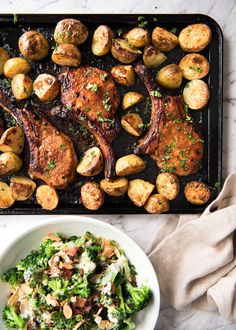 a plate of food with meat, potatoes and broccoli on it next to a bowl of salad