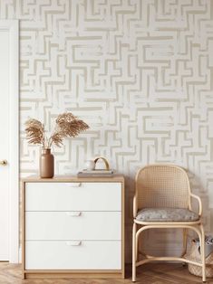 a white chair sitting next to a dresser in front of a wall with a pattern on it