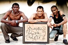 three men sitting next to each other holding a sign