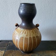 a brown and black vase sitting on top of a table