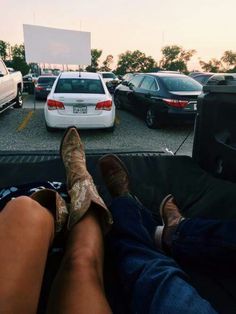 two people are sitting in the back of a truck with their feet on the ground