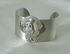 "This beautiful bracelet has a silver plated cuff with silver plated art nouveau maiden and silver plated leaf accents. 1.5\" wide." Victorian Hallmarked Silver Cuff Bracelet, Victorian Silver Hallmarked Cuff Bracelet, Victorian Hallmarked Cuff Bracelet As A Gift, Antique Silver Cuff Bracelet As Gift, Handmade Victorian Silver Cuff Bracelet, Adjustable Silver Art Deco Bracelets, Victorian Style Handmade Silver Cuff Bracelet, Art Deco Bangle Jewelry As A Gift, Art Deco Bangle Jewelry For Gifts