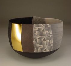 a black and gold bowl sitting on top of a white table next to a gray wall