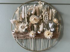 a circular metal rack with flowers and feathers on the wall next to a gray wall