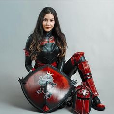 a woman sitting on the ground with a shield and armor