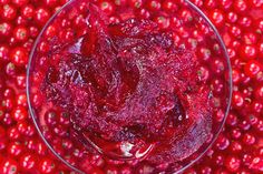 a glass bowl filled with cranberry sauce sitting on top of a pile of cranberries