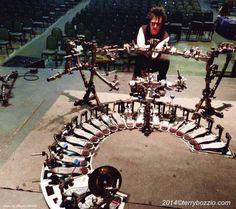 a man kneeling down next to a large set of musical instruments on the ground in front of rows of chairs