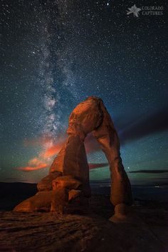 the night sky is filled with stars, and there are rocks in front of it