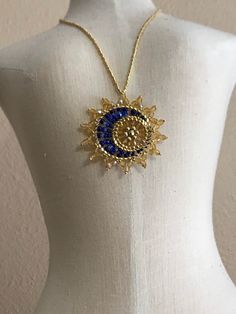 "Sun & Moon Beaded Celestial Statement Necklace.  This unique pendant is an inspirational and captivating statement piece.  It is a dramatic and eye-catching Made to Order piece which captures a delicate cool blue moon in front of a brilliant golden sun.  The pendant is stationary on a neckline of galvanized gold tiny seed beads and fastens with a gold plated lobster claw.  The pendant diameter is approximately 1 3/4\".  The shades of blue may vary.  Choose your desired length at checkout.  The pendant is dipped in floor wax to prevent the sun rays from flopping.  All materials used are Nickel/Lead Free.  Designed by Sara Landry, Dragonfly Lane and brought to life by Krina Kreations." Celestial Gold Jewelry For Festivals, Gold Jewelry With Moon Charm For Party, Gold Crescent Jewelry For Party, Bohemian Moon Charm Jewelry For Party, Moon Charm Pendant Jewelry For Party, Party Moon Charm Pendant Jewelry, Celestial Gold Necklace For Festival, Party Pendant Jewelry With Moon Charm, Gold Sun And Moon Design Jewelry For Festivals