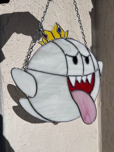 a stained glass ghost hanging from a chain with a crown on it's head