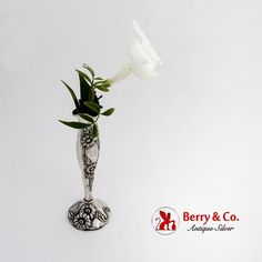 a white flower in a silver vase on a white background with berry & co logo