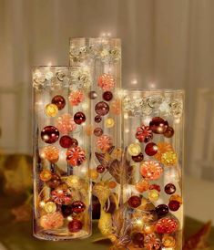 two vases filled with different types of glass beads and flowers on top of a table