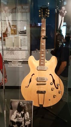 an electric guitar is on display in a glass case with a black and white photo next to it