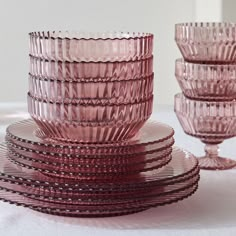 a stack of pink glass dishes sitting on top of a table