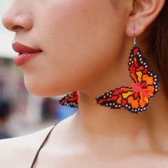 a close up of a person wearing earrings with a butterfly design on the back of their ear