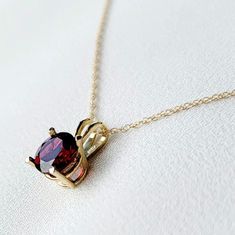 A stunning red garnet necklace, crafted with exquisite detail, featuring a rich and vibrant garnet pendant as the focal point. The deep red gemstone is elegantly set in a fine metal setting of your choice, complemented by a delicate chain. This timeless piece adds a touch of sophistication and warmth to any attire, making it a perfect accessory for both casual and formal occasions. These necklaces are available in your choice of a 14k solid gold setting (yellow or rose gold), or .925 solid silve Yellow Gold Garnet Necklaces With Oval Shape, Yellow Gold Oval Garnet Necklace, Garnet Birthstone Necklaces In Fine Jewelry Style, Garnet Birthstone Necklace In Fine Jewelry Style, Garnet Birthstone Fine Jewelry Necklace, Elegant Oval Garnet Necklace, Red Garnet Oval Pendant Necklace, Fine Jewelry Yellow Gold Garnet Necklaces, Round Garnet Gemstone Necklaces